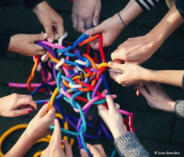 Viele Hände halten Seile, die zu einem Knoten gesponnen wurden