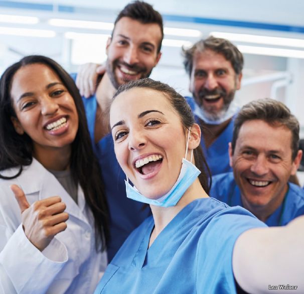 Hände einer jungen Person drücken die Hände einer älteren Person, die im Rollstuhhl sitzt.