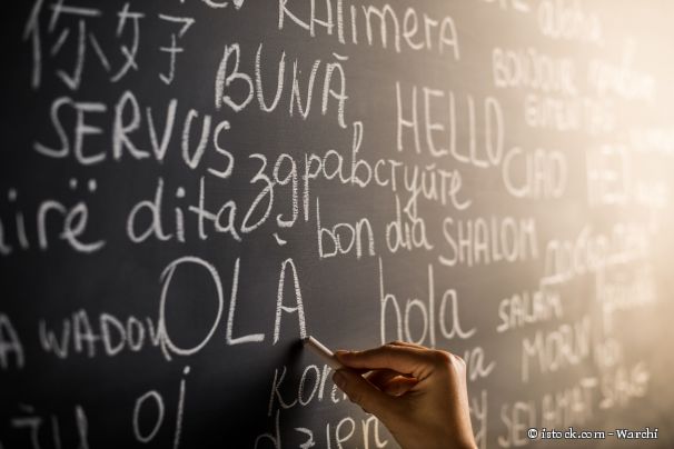 Auf einer Tafel steht das Wort Hallo in verschiedenen Sprachen, unter anderem hola, servus, hello oder shalom.