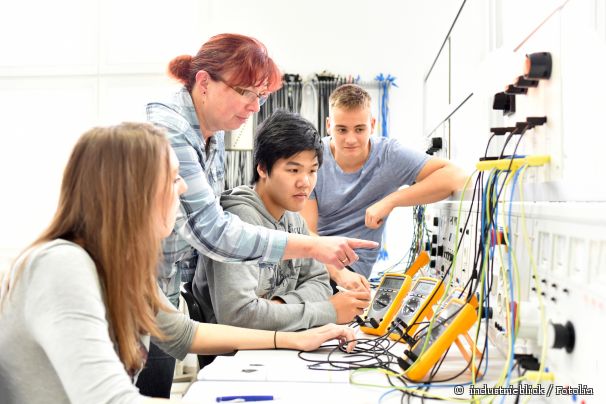 Jugendliche schauen sich unter Anleitung elektrische Leitungen an.